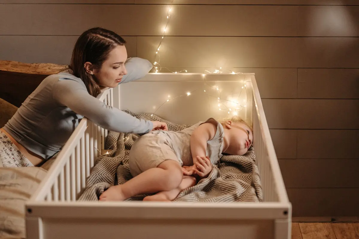 Una mamá mira a su bebé dormido en la cuna